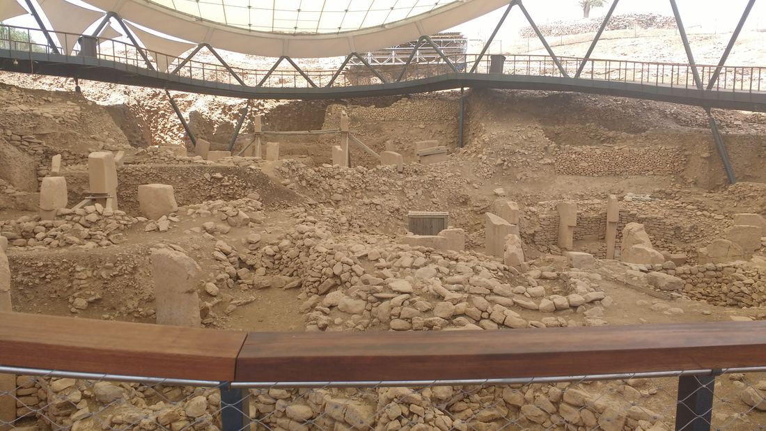 View from a visitor walkway over the excavated stone enclosures of Göbekli Tepe under a large protective roof
