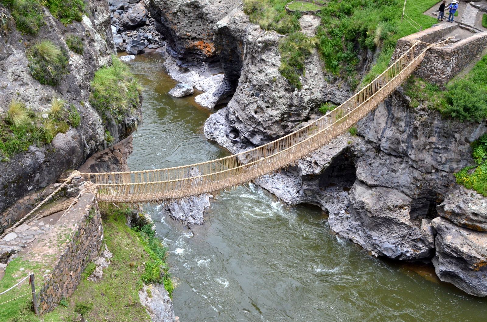 The Q'eswachaka rope suspension bridge, woven from grass, hanging across a rocky gorge above the rushing Apurímac River in Peru
