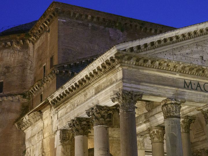 The columned portico and massive concrete drum and dome of the Pantheon in Rome against a deep blue evening sky